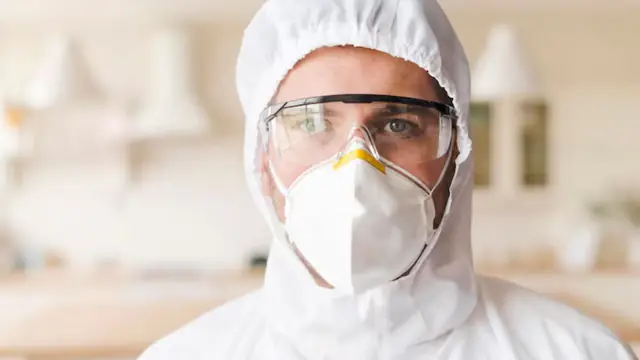 Mold remediation worker in a respirator and protective hood