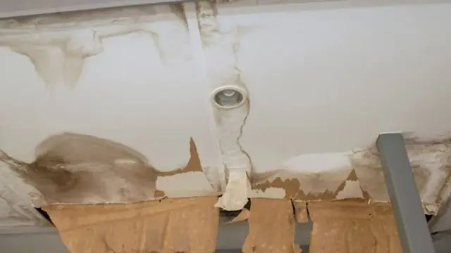 Stained and sagging ceiling around a light fixture after a leak